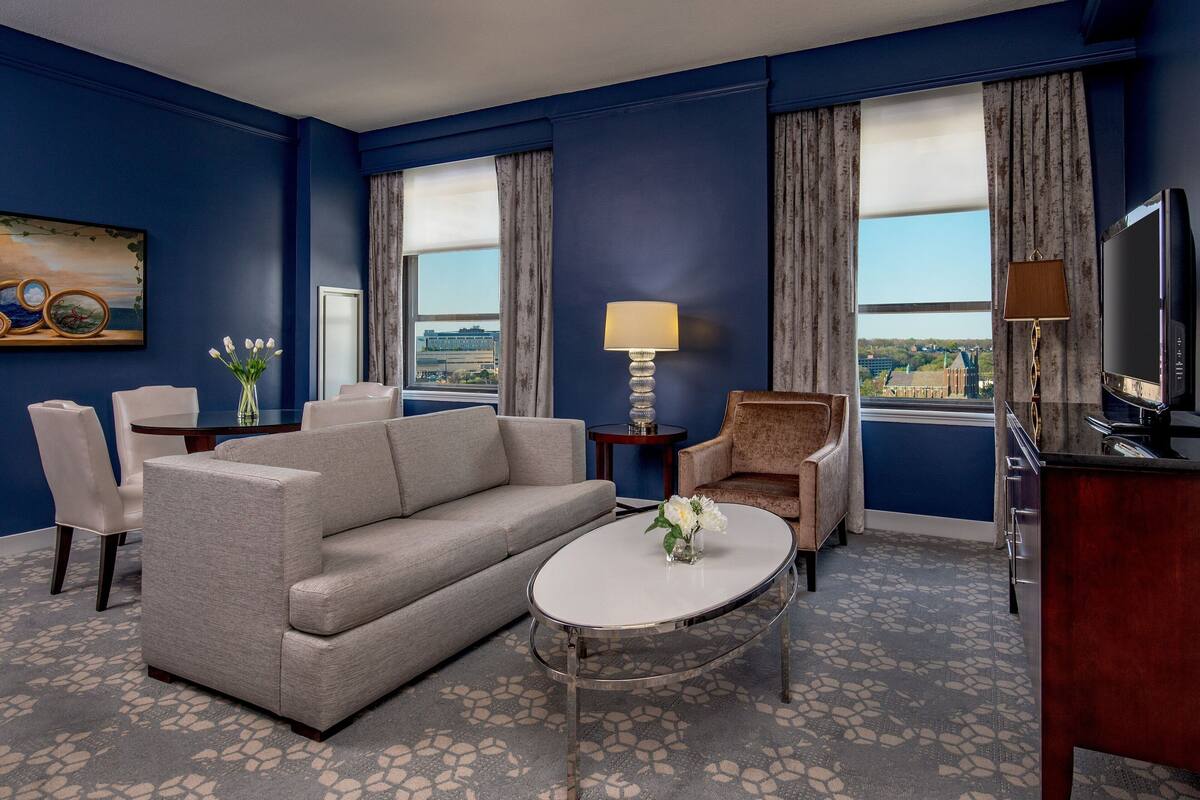 Een hotelkamer met een bank, fauteuil, salontafel en een televisie.