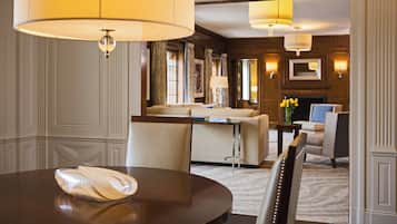 A hotel room with a round dining table, a sofa, a chair, and a fireplace.