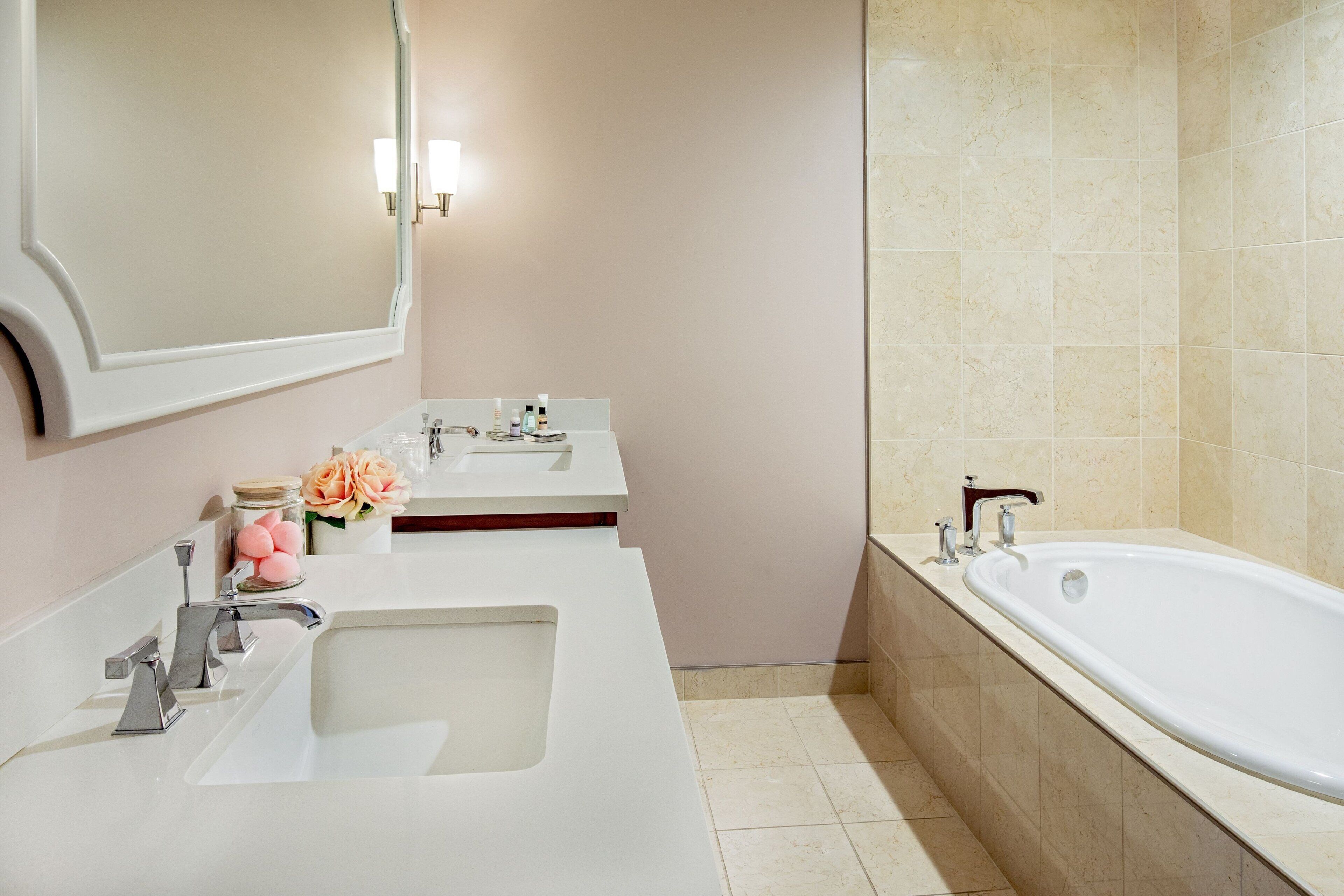 A bathroom with a large bathtub, two sinks, and a mirror.