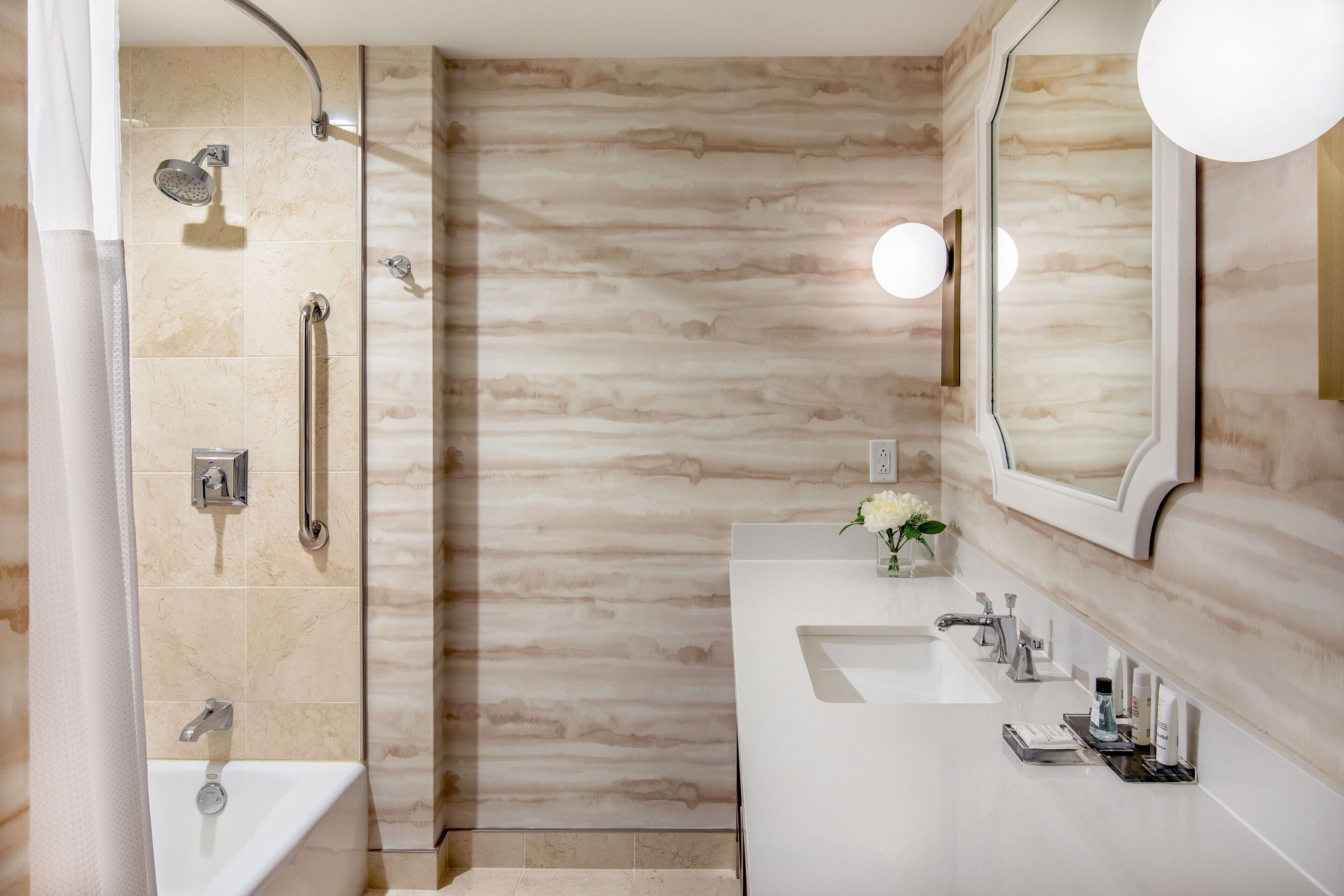A modern bathroom with a walk-in shower, a vanity with a mirror, and a sink.