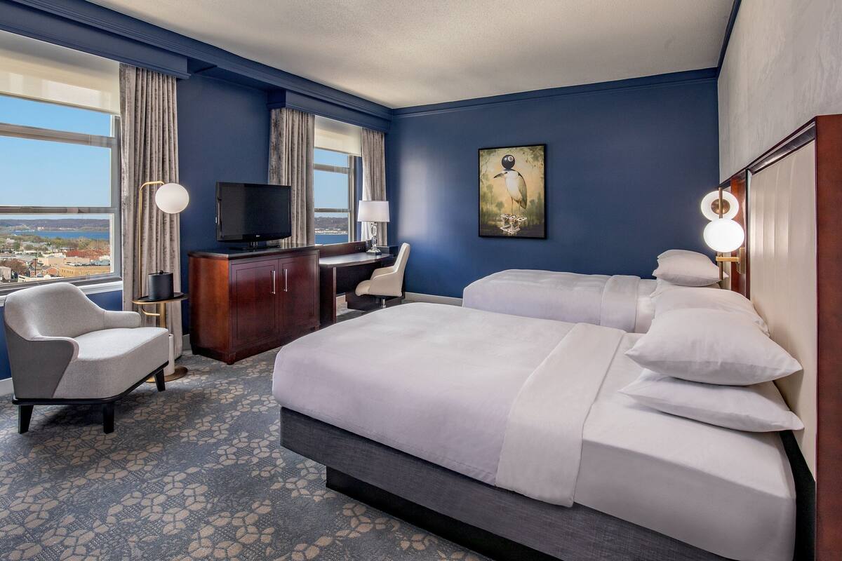Hotelkamer met een groot bed, een bureau, een stoel, een televisie en uitzicht op de stad.