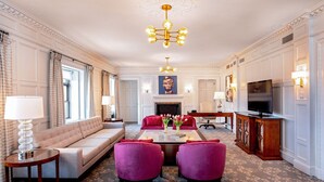 Un salon spacieux comprenant un canapé, deux fauteuils, une table basse et une cheminée.