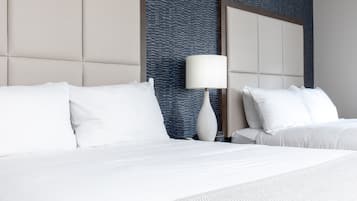 A hotel room with a large bed, white bedding, a nightstand with a lamp, and a textured blue wall.