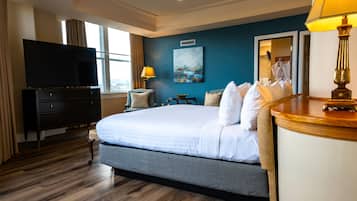 A hotel room with a large bed, a flat-screen TV, a desk with a lamp, and a painting on the wall.