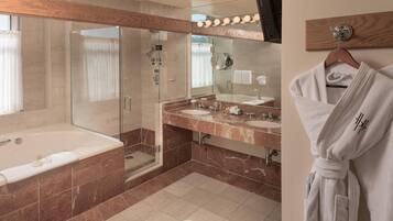 Een moderne badkamer met een douchecabine van glas, een ruim bad en twee wastafels.