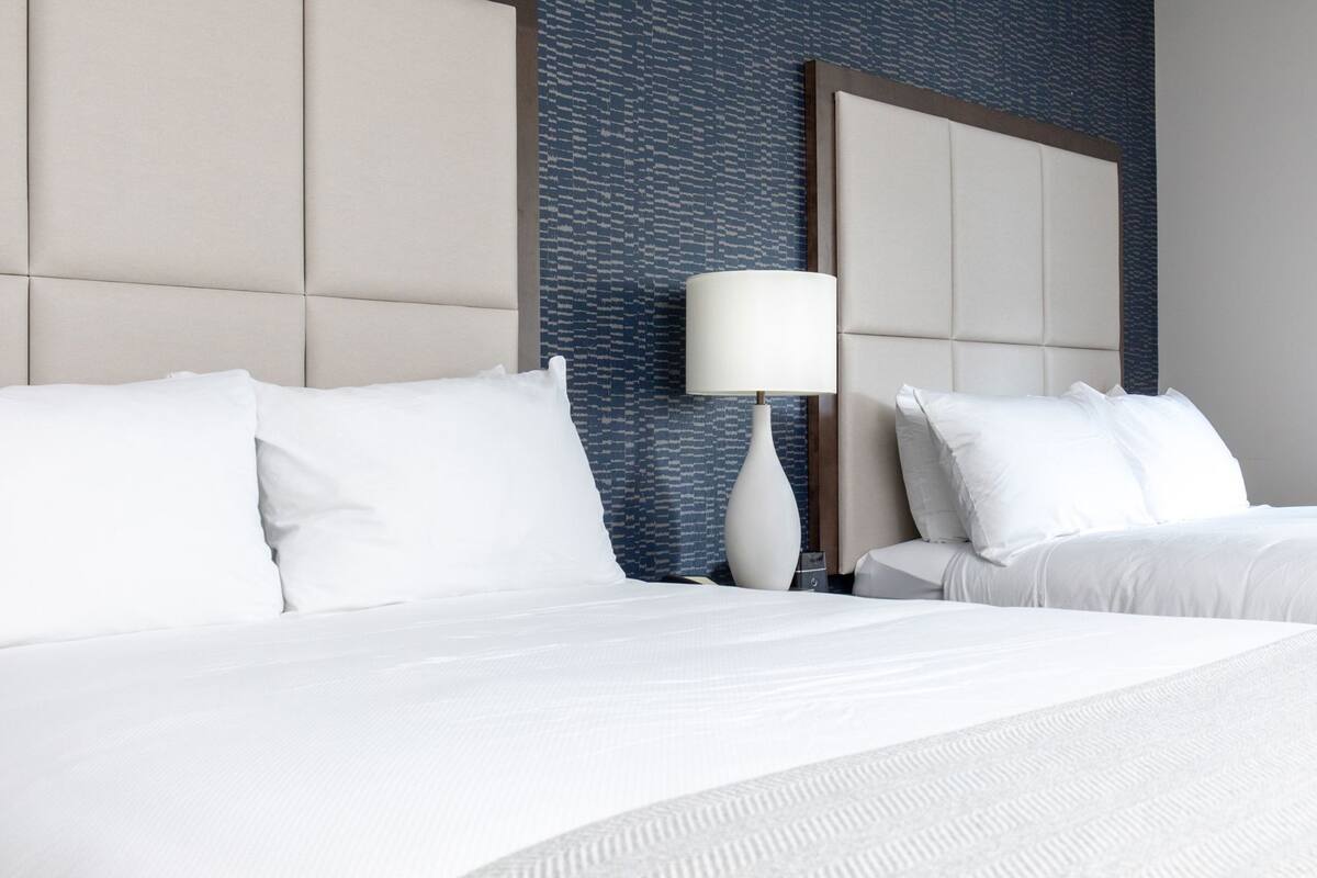 Une chambre d’hôtel avec un grand lit, deux tables de chevet, une lampe et un mur décoré d’un motif.