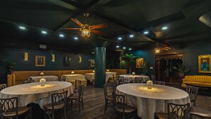 Een restaurant met ronde tafels, houten vloeren en een plafondventilator.