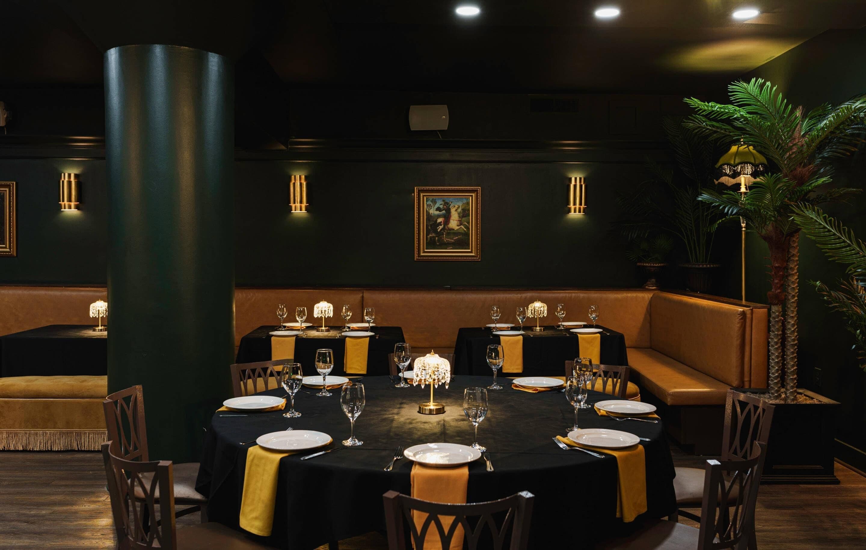 Une salle à manger à la lumière tamisée, avec des tables rondes dressées pour le repas, agrémentées de centres de table à bougies et d’un éclairage chaleureux.