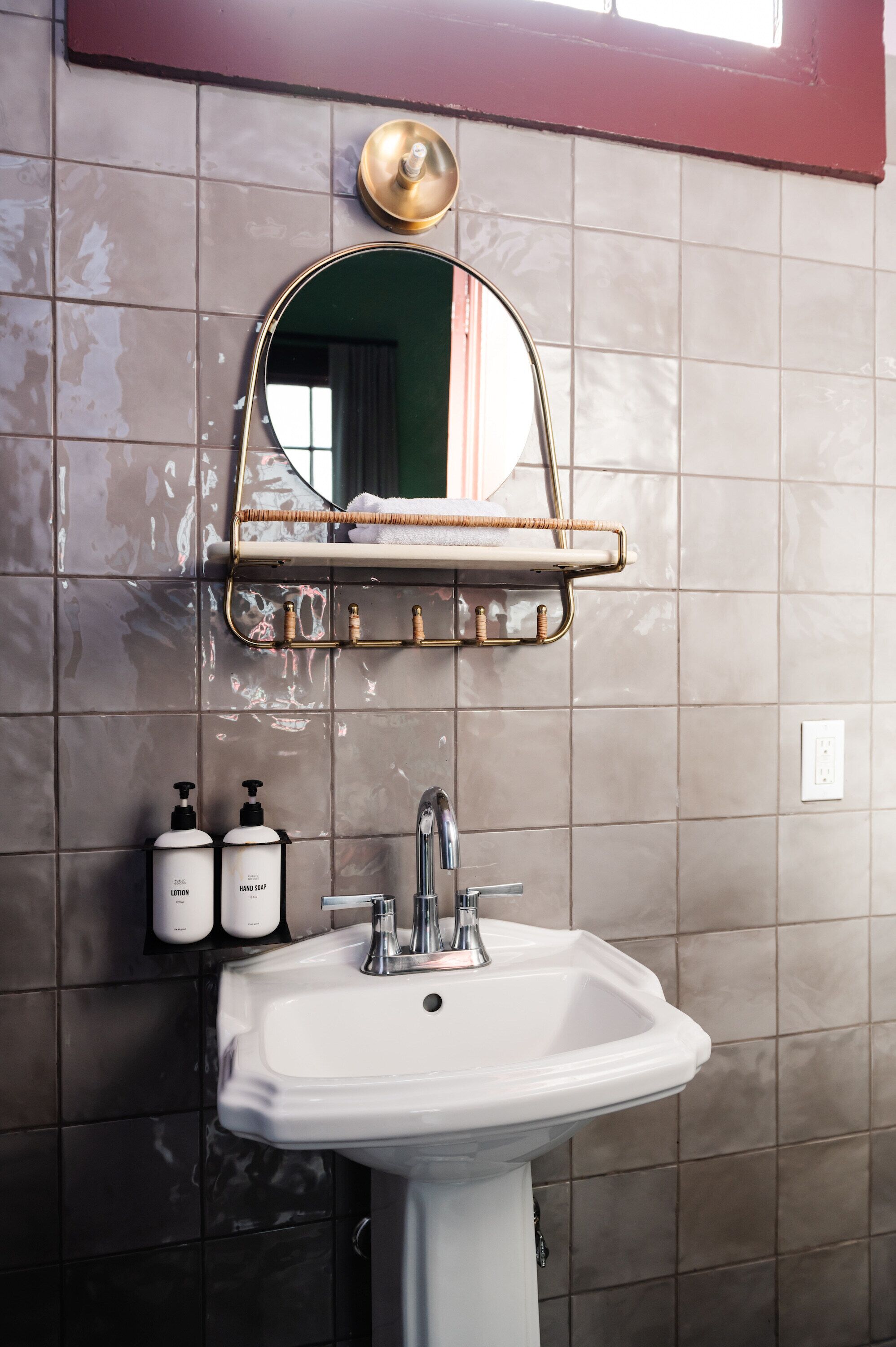 A bathroom with a white sink, a mirror with a gold frame, and two bottles of soap.