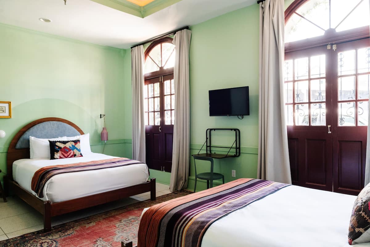 A room with two beds, a television, and a window with curtains.