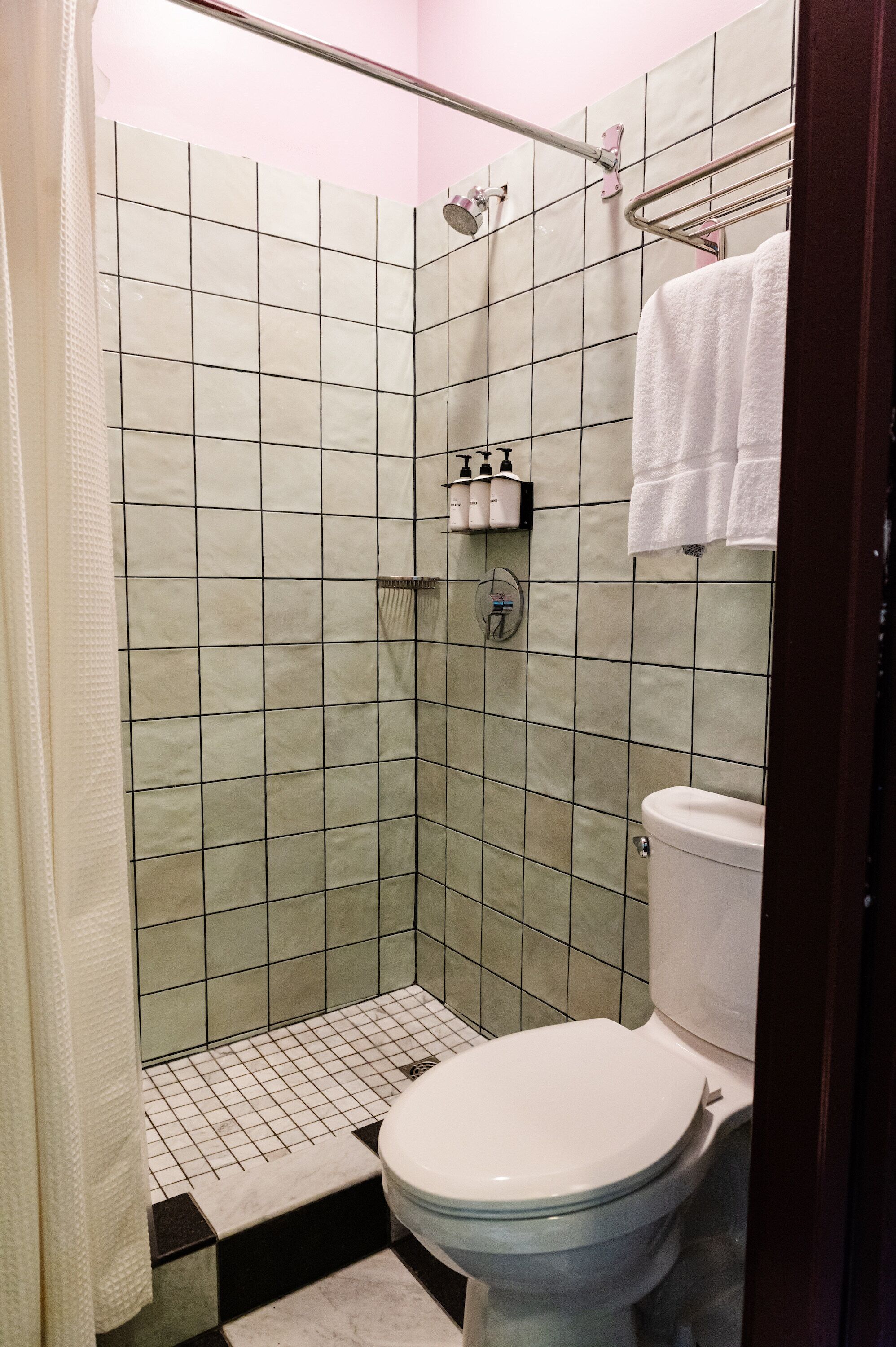 Een badkamer met douche, toilet en betegelde wanden.