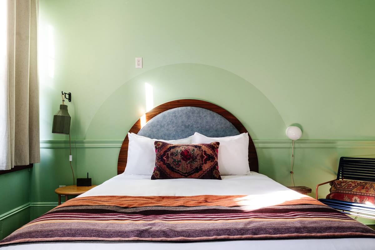 A bed with a wooden headboard, a patterned pillow, and a striped blanket.