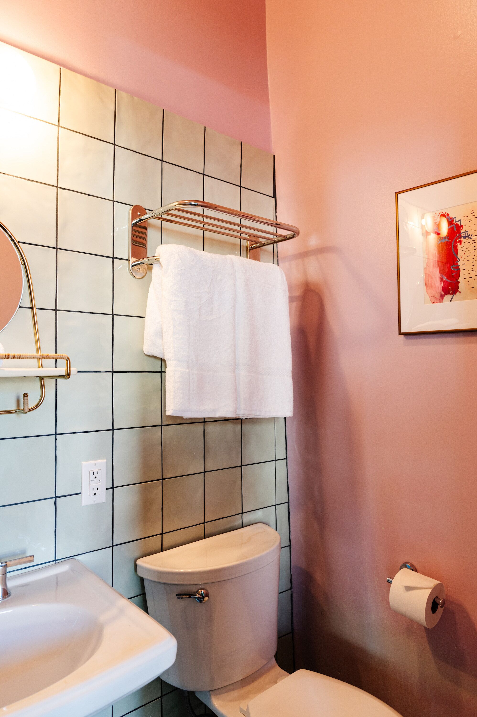 Un baño con inodoro, lavamanos y perchero para toallas.