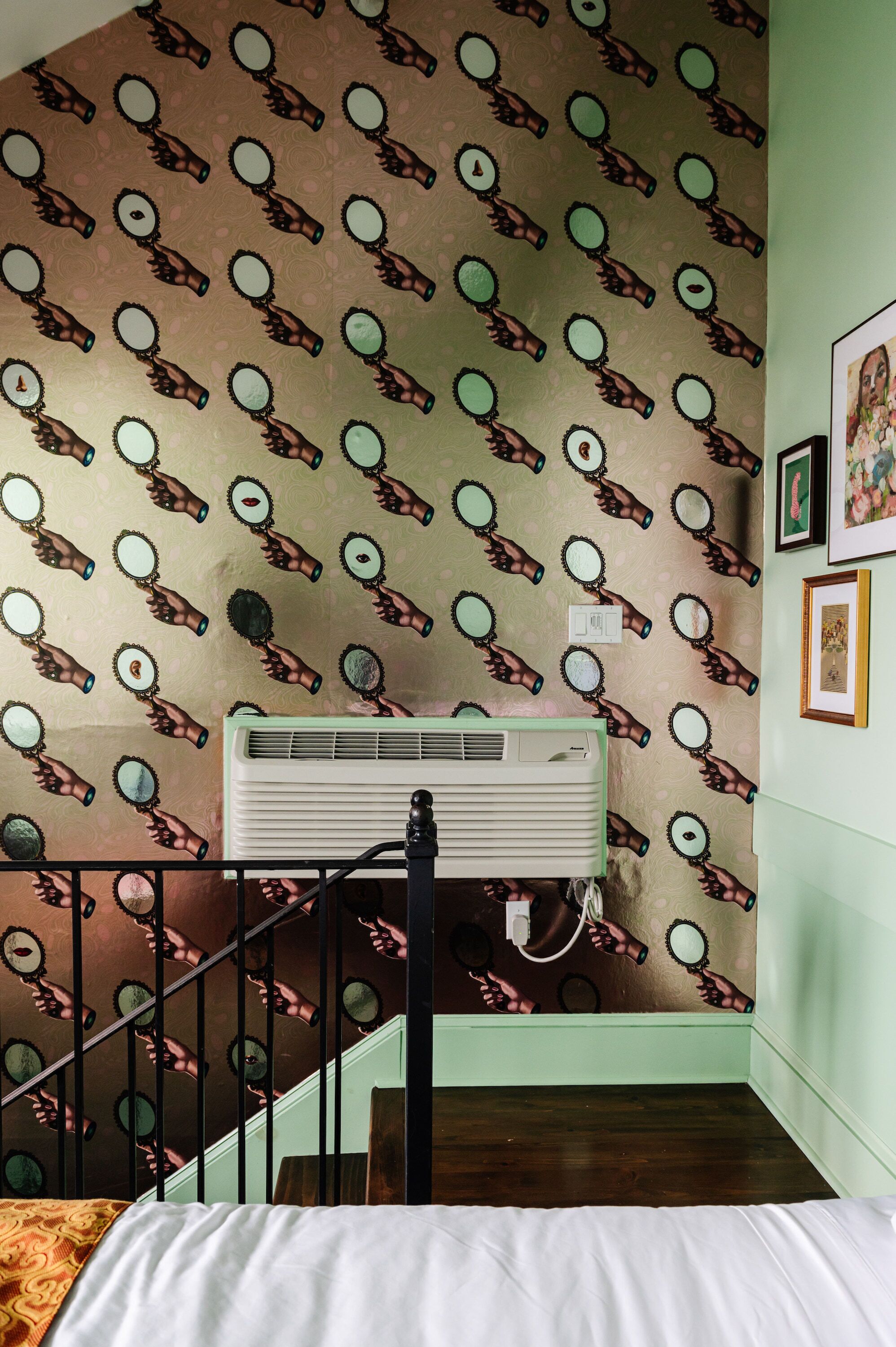 Une pièce avec un papier peint à motifs, un escalier et un lit.