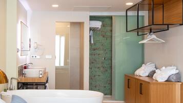 Un baño moderno con una bañera grande, un tocador de madera y una pared de ladrillo verde.