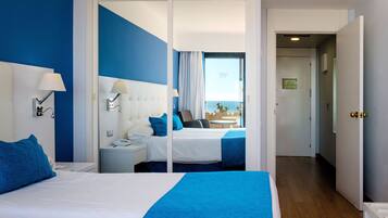 Habitación de hotel con dos camas, vista al mar y balcón.