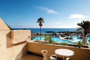 A pool area with multiple sections, palm trees, and umbrellas. - Alexandre Grand Teguise Playa (Teguise)