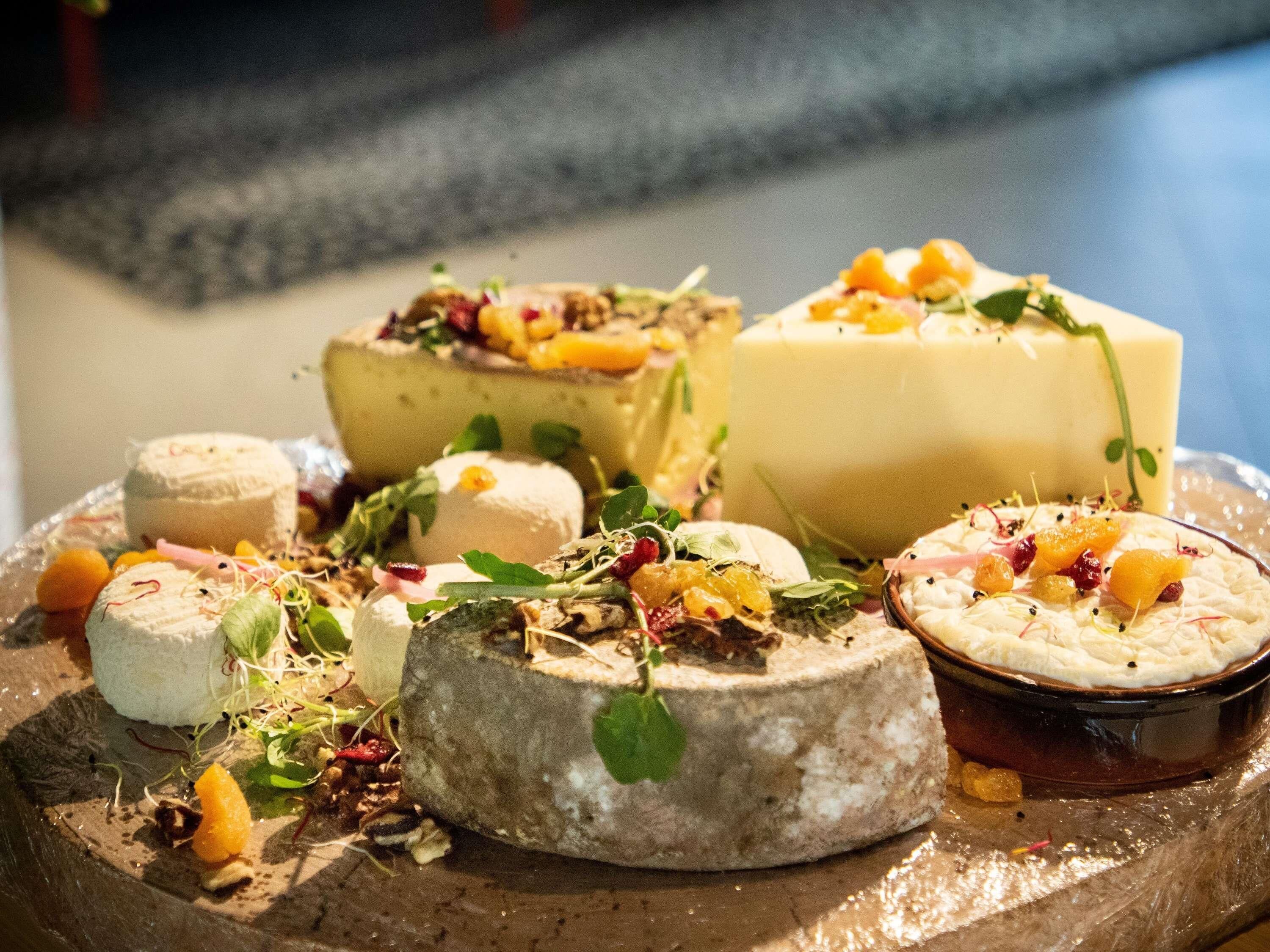 A variety of cheeses and fruits on a wooden board.