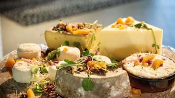 A variety of cheeses and fruits on a wooden board.