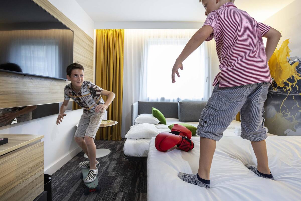 A hotel room with a bed, a desk, and a mirror.