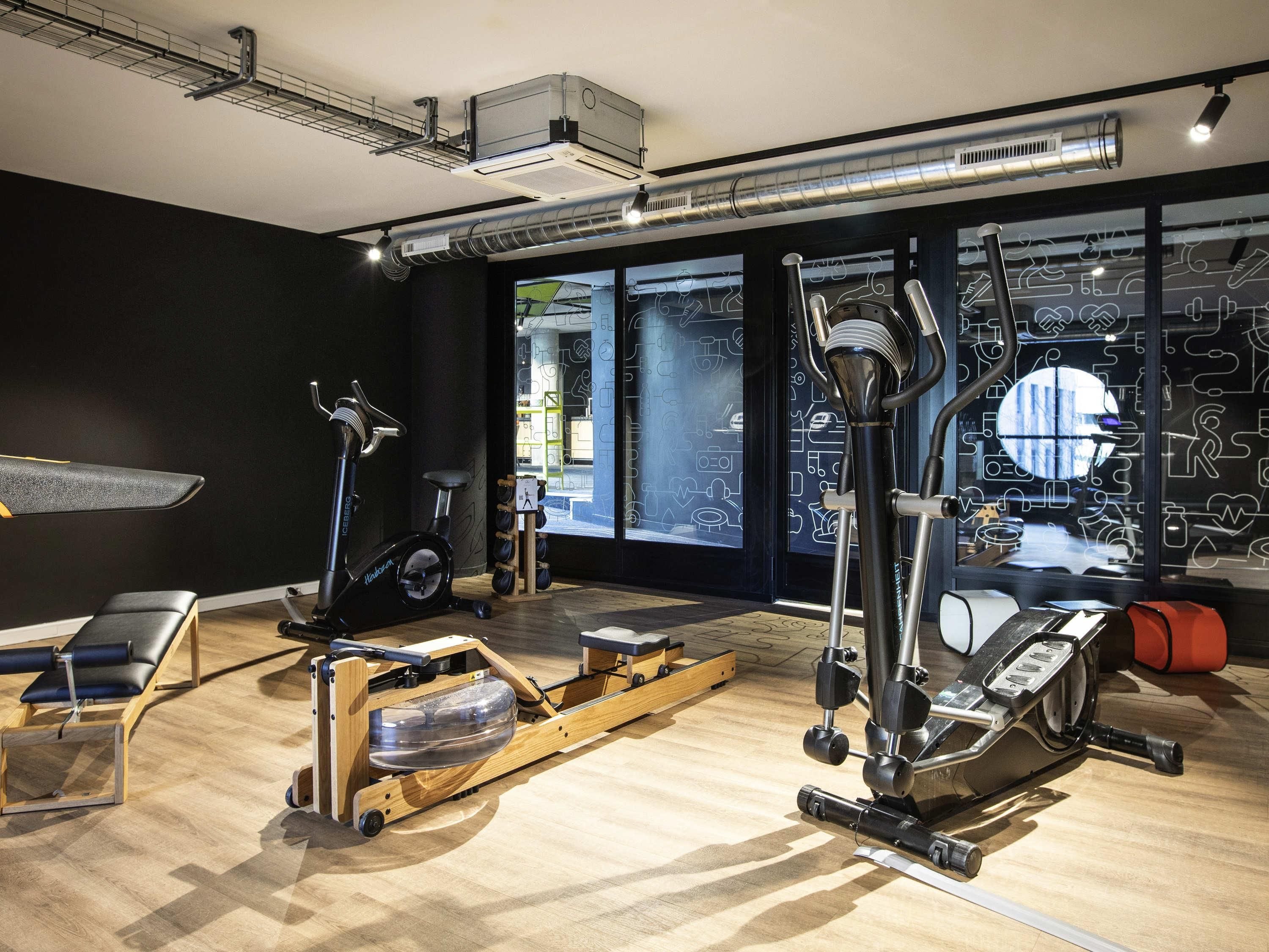 A gym with exercise equipment, a rowing machine, and a bench.