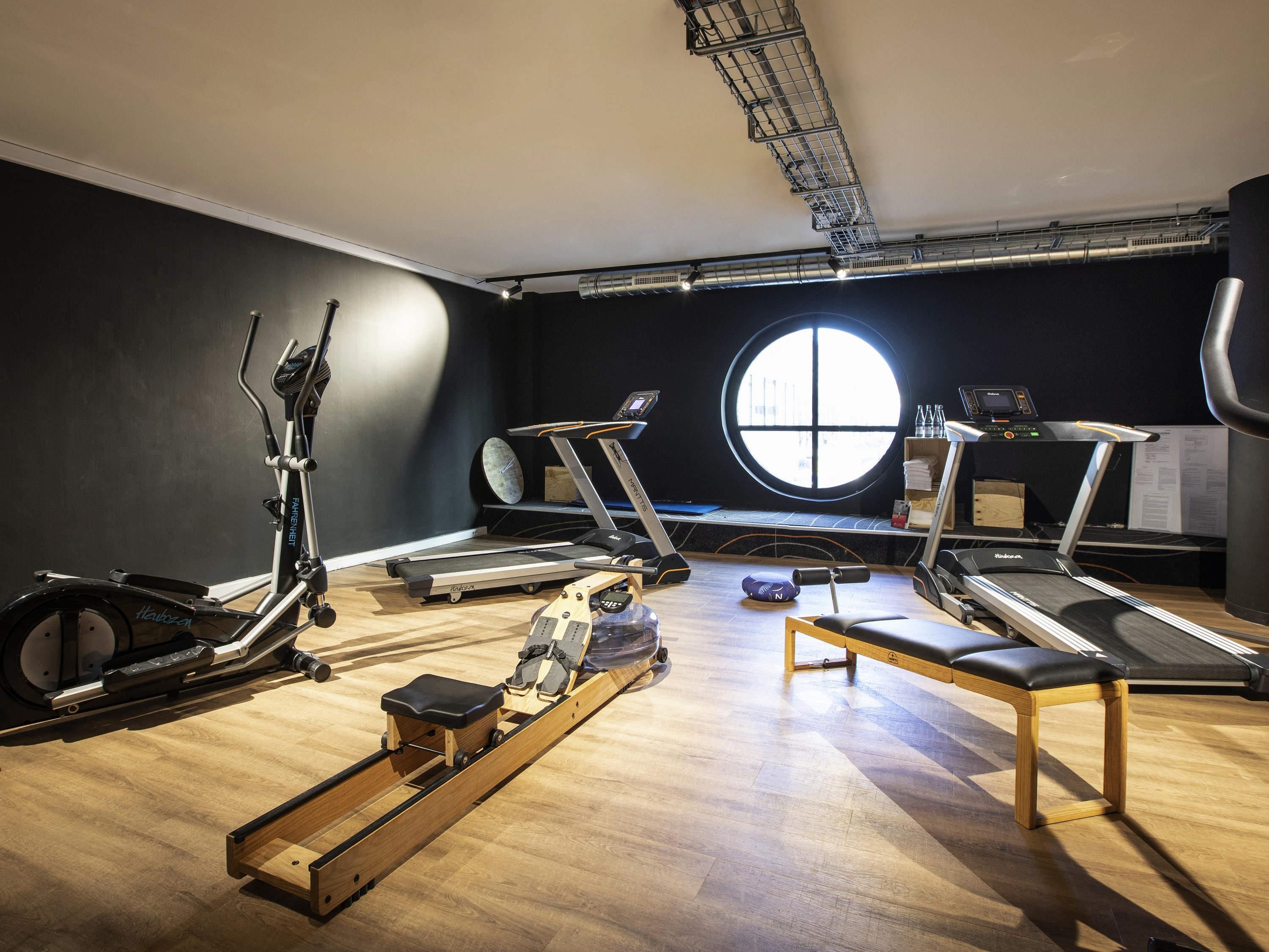 Un gimnasio con cintas de correr, bicicletas estáticas y una máquina de remo.