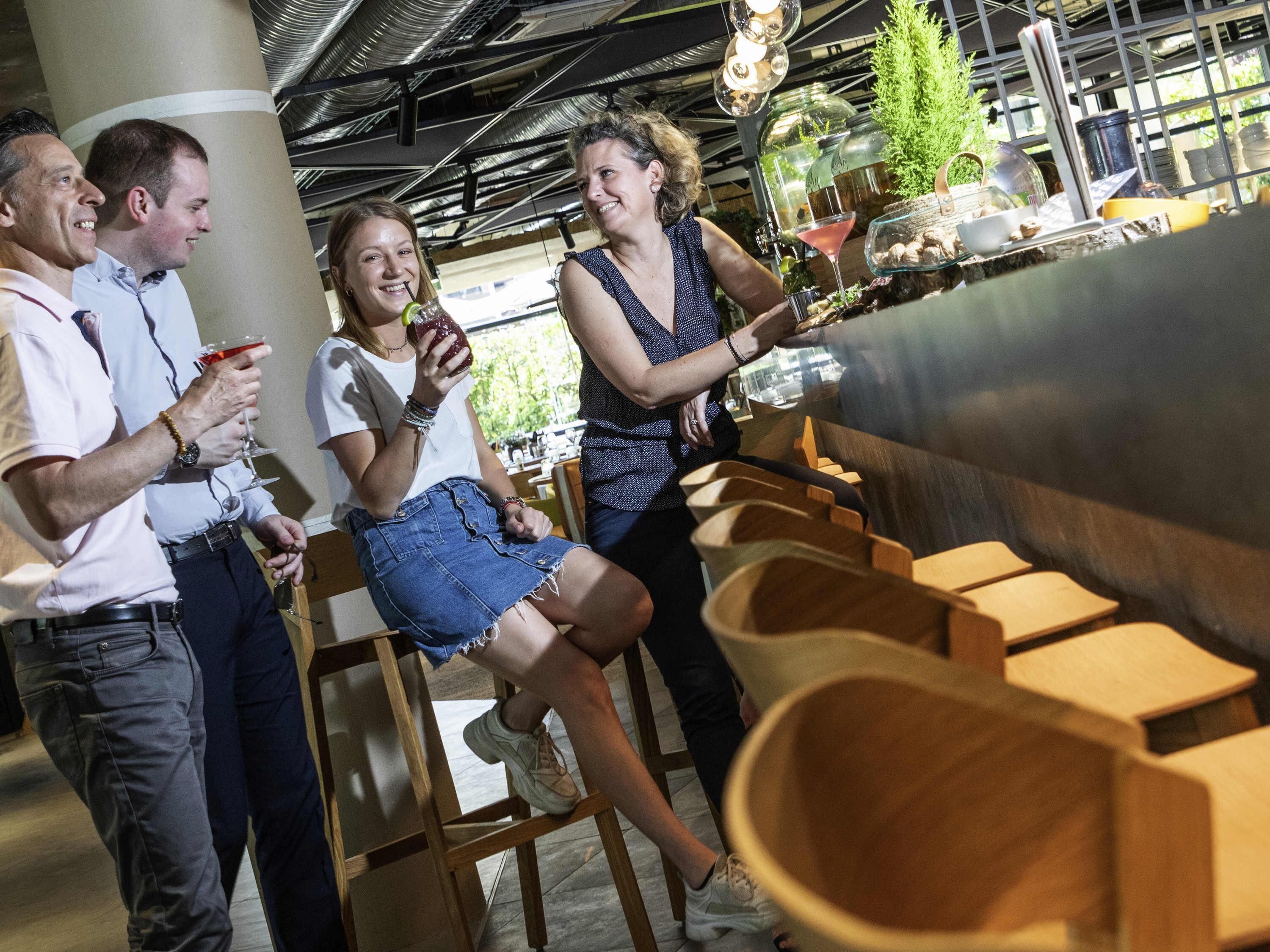 Un groupe de personnes se trouve dans un espace intérieur moderne, avec des meubles en bois et un plafond haut.