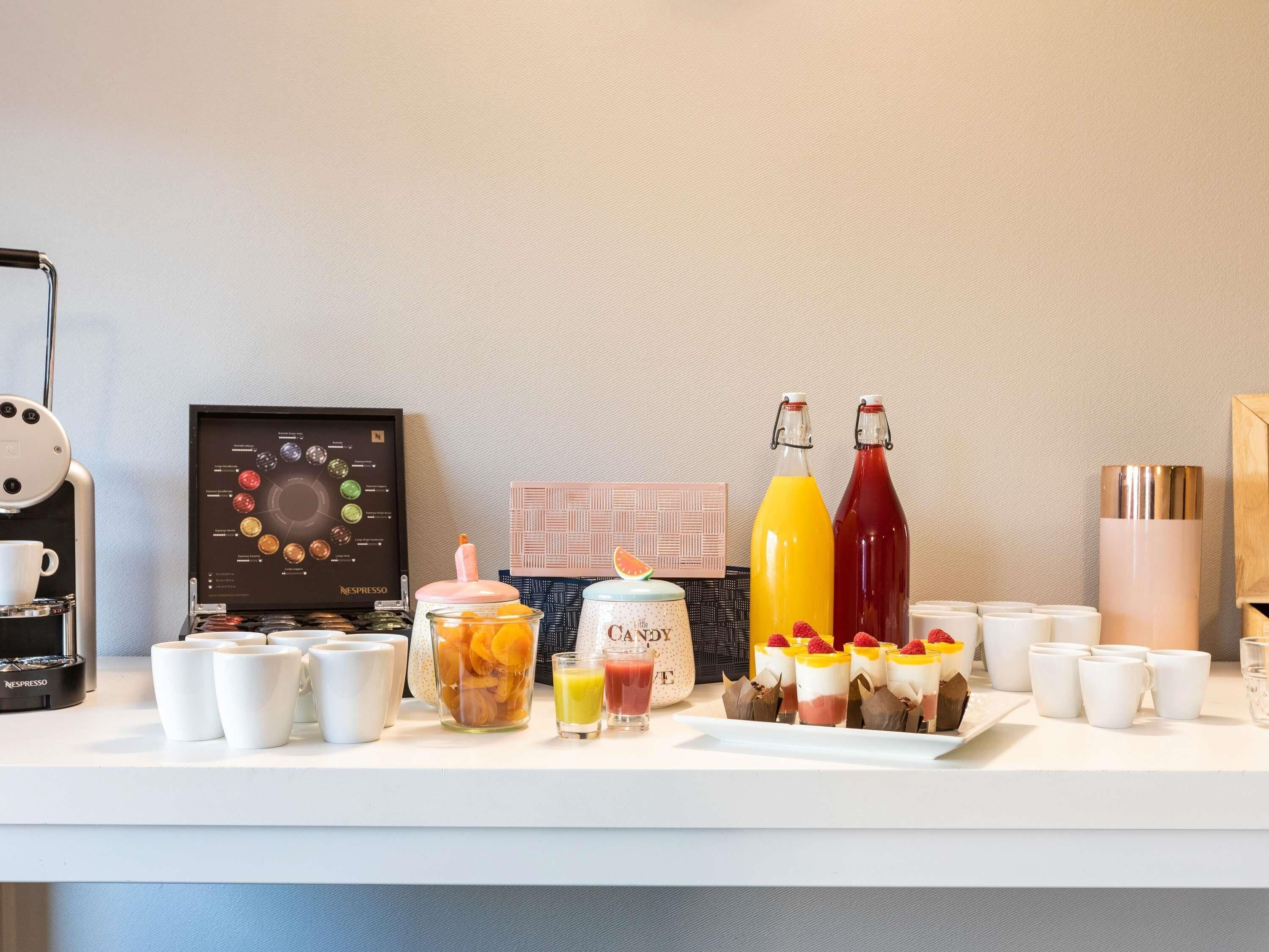 A breakfast buffet with a coffee machine, a variety of beverages, and a selection of pastries.
