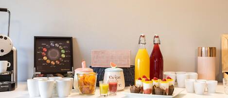 A breakfast buffet with a coffee machine, a variety of beverages, and a selection of pastries.