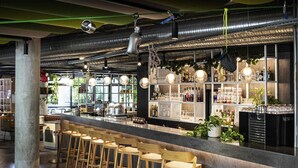 A bar area with wooden stools, a counter with bottles, and hanging lights. - Novotel Annecy Centre (Annecy)
