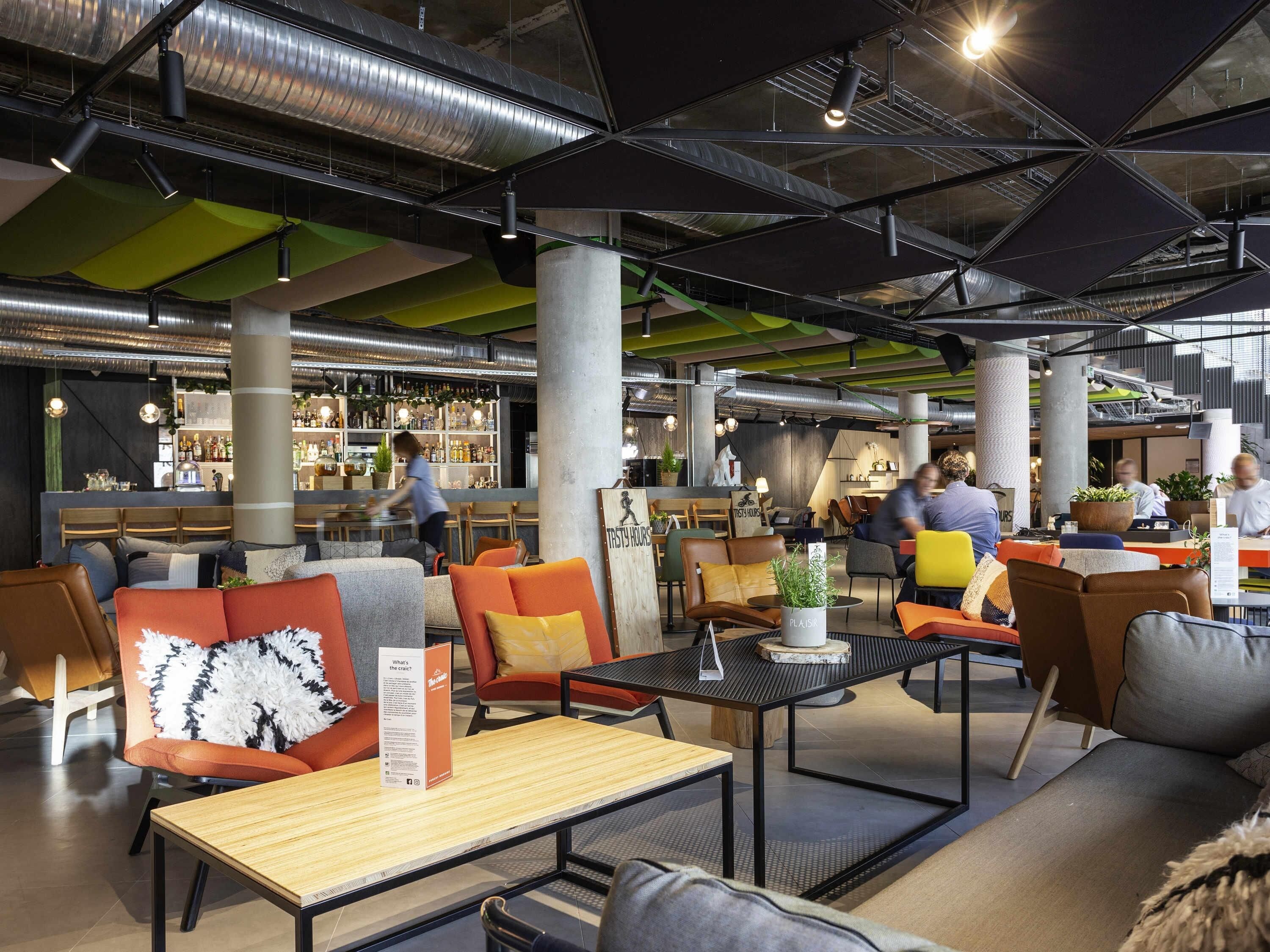 Un intérieur moderne avec des espaces de détente, un bar et du matériel de cuisine visible.