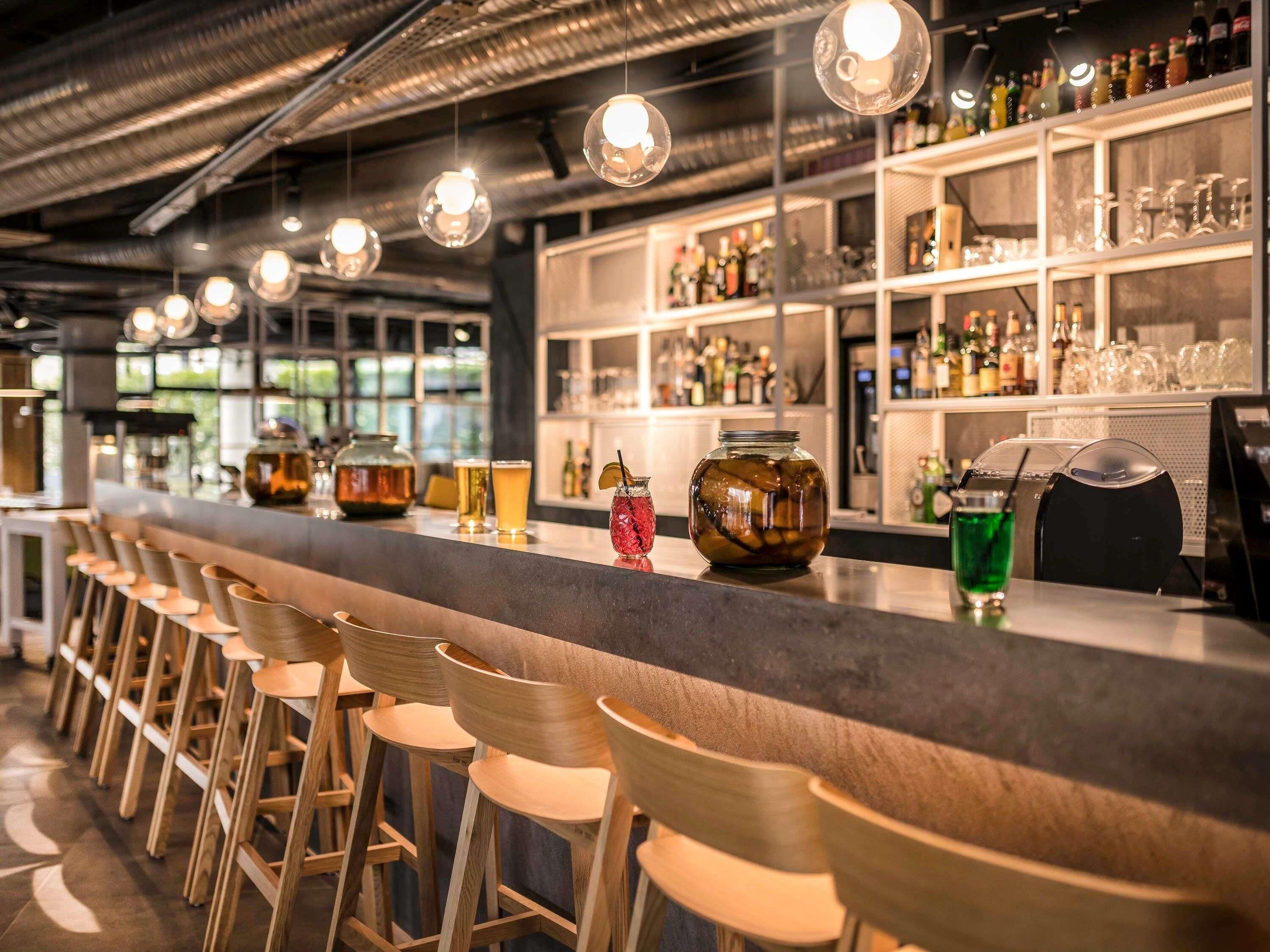 Un espace bar avec des tabourets, un comptoir et des étagères remplies de bouteilles et de verres.