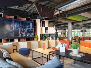 Un espace détente moderne avec des sièges, un téléviseur et un bar à café.