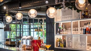 A bar area with hanging spherical light fixtures, a bar counter, and shelves stocked with bottles and glasses. - Novotel Annecy Centre (Annecy)
