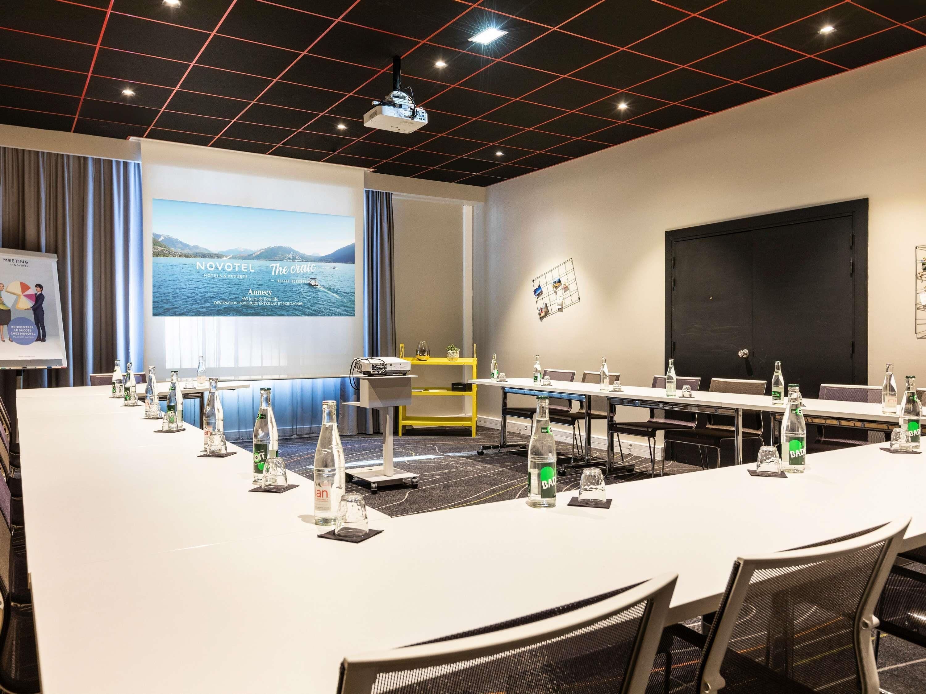 Une salle de conférence équipée d’une longue table, de chaises, d’un projecteur et d’un écran diffusant une vue panoramique.
