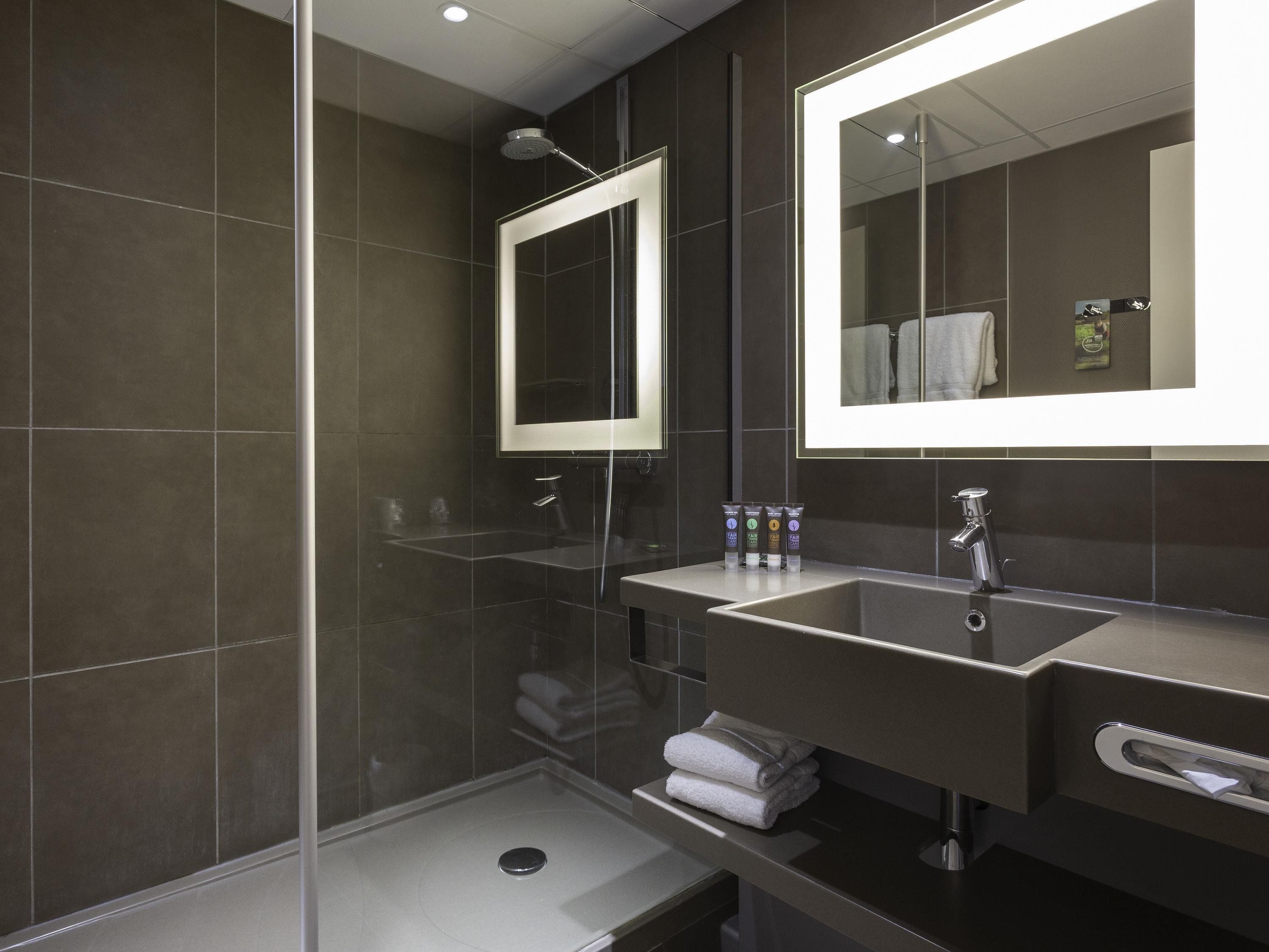 A modern bathroom with a glass-enclosed shower, a vanity with a mirror, and a towel rack.