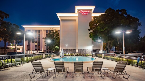 Hotel met zwembad, terras en neonreclame.