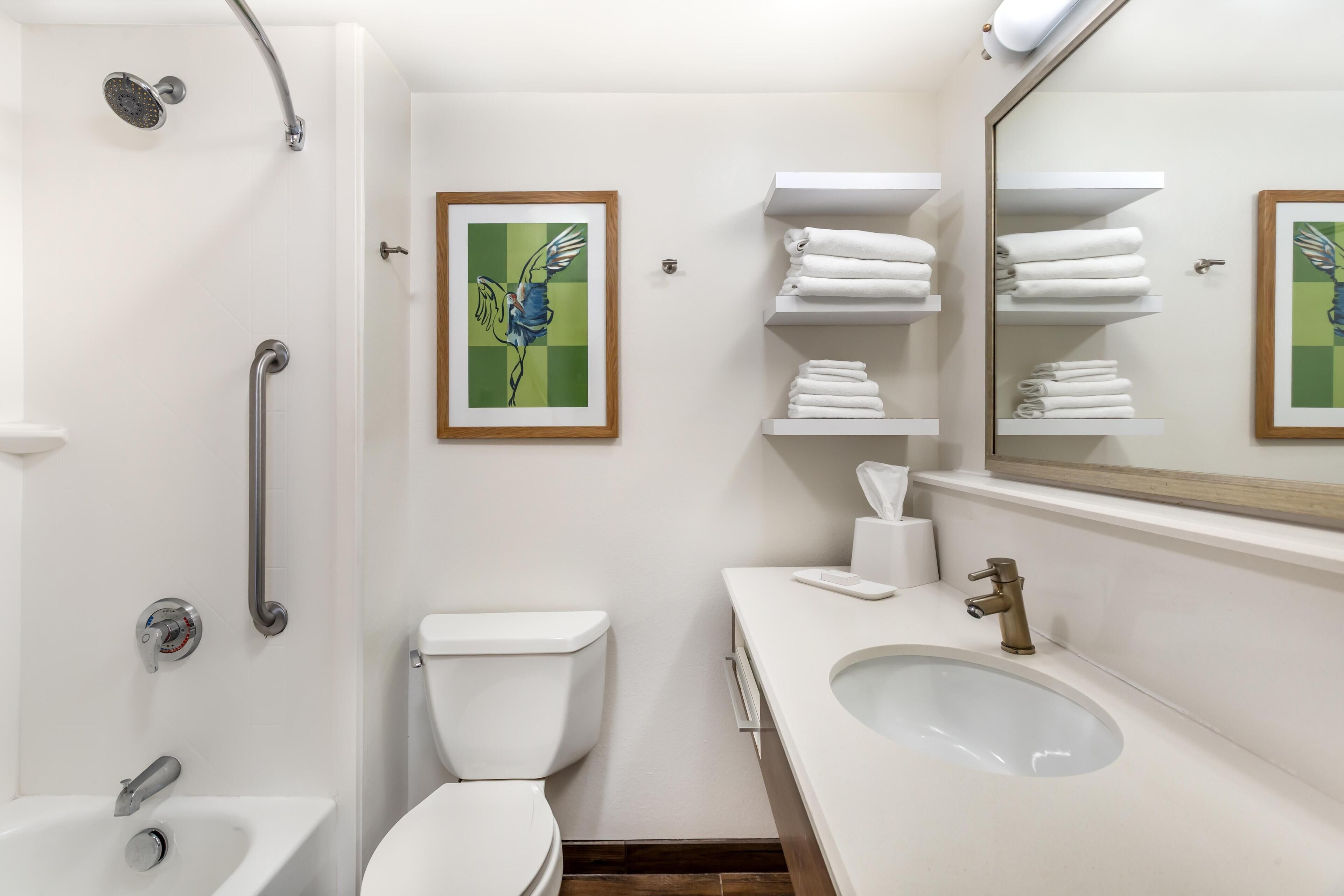 A modern bathroom with a shower, toilet, sink, and towel racks.