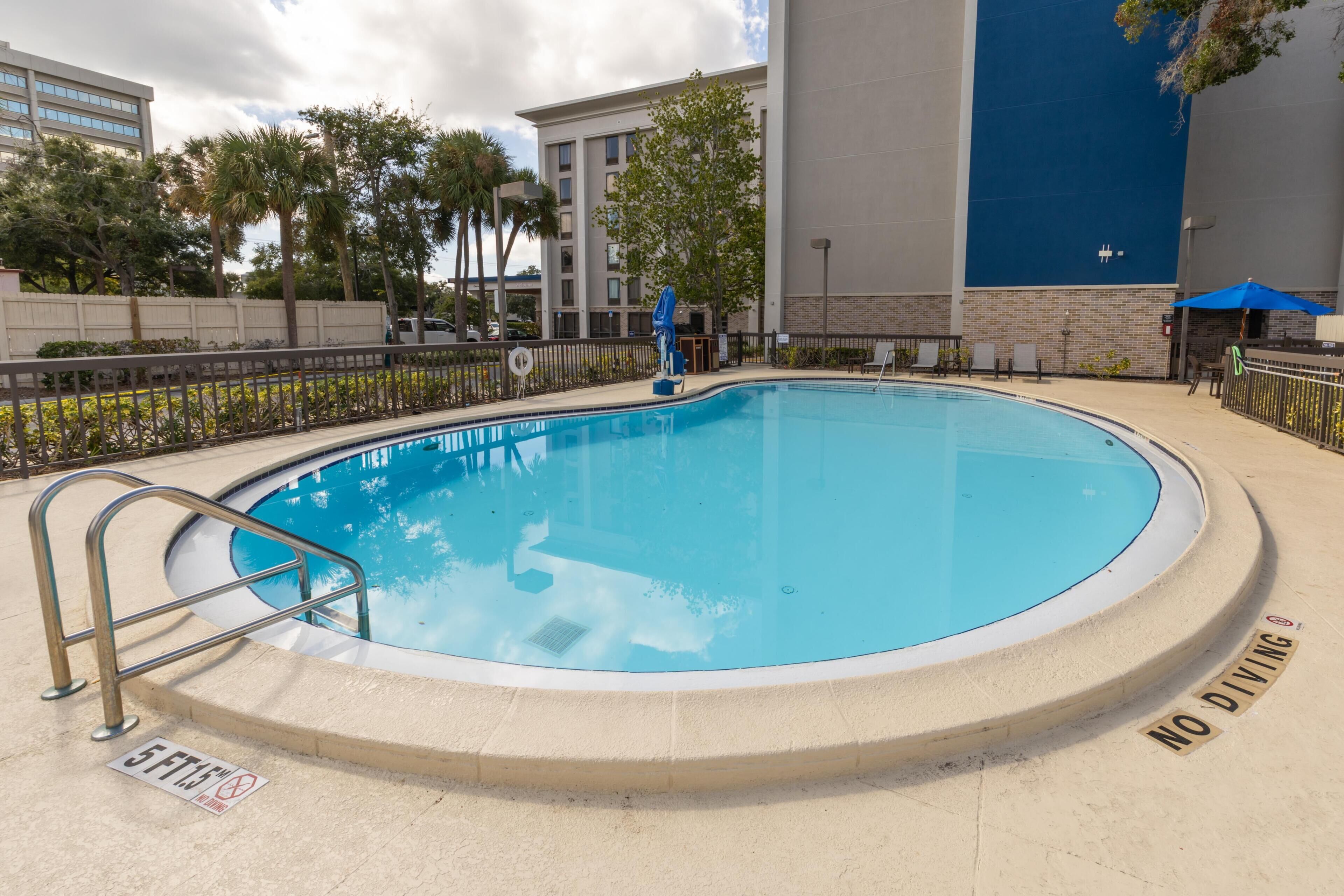 Una piscina con un letrero que dice 'NO DIVING', una marca de profundidad de 1,5 metros y una sombrilla azul.