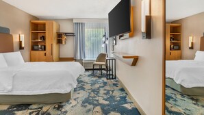 Een hotelkamer met twee bedden, een televisie, een bureau, een stoel en een raam met gordijnen.