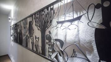 A wall with a metal art piece depicting abstract shapes and figures.