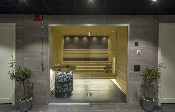 Una entrada moderna y bien iluminada con una recepción, un área de descanso y dos plantas en macetas.