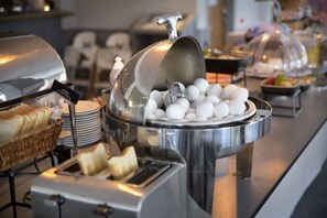 A buffet with a variety of food items including eggs, bread, and fruits.