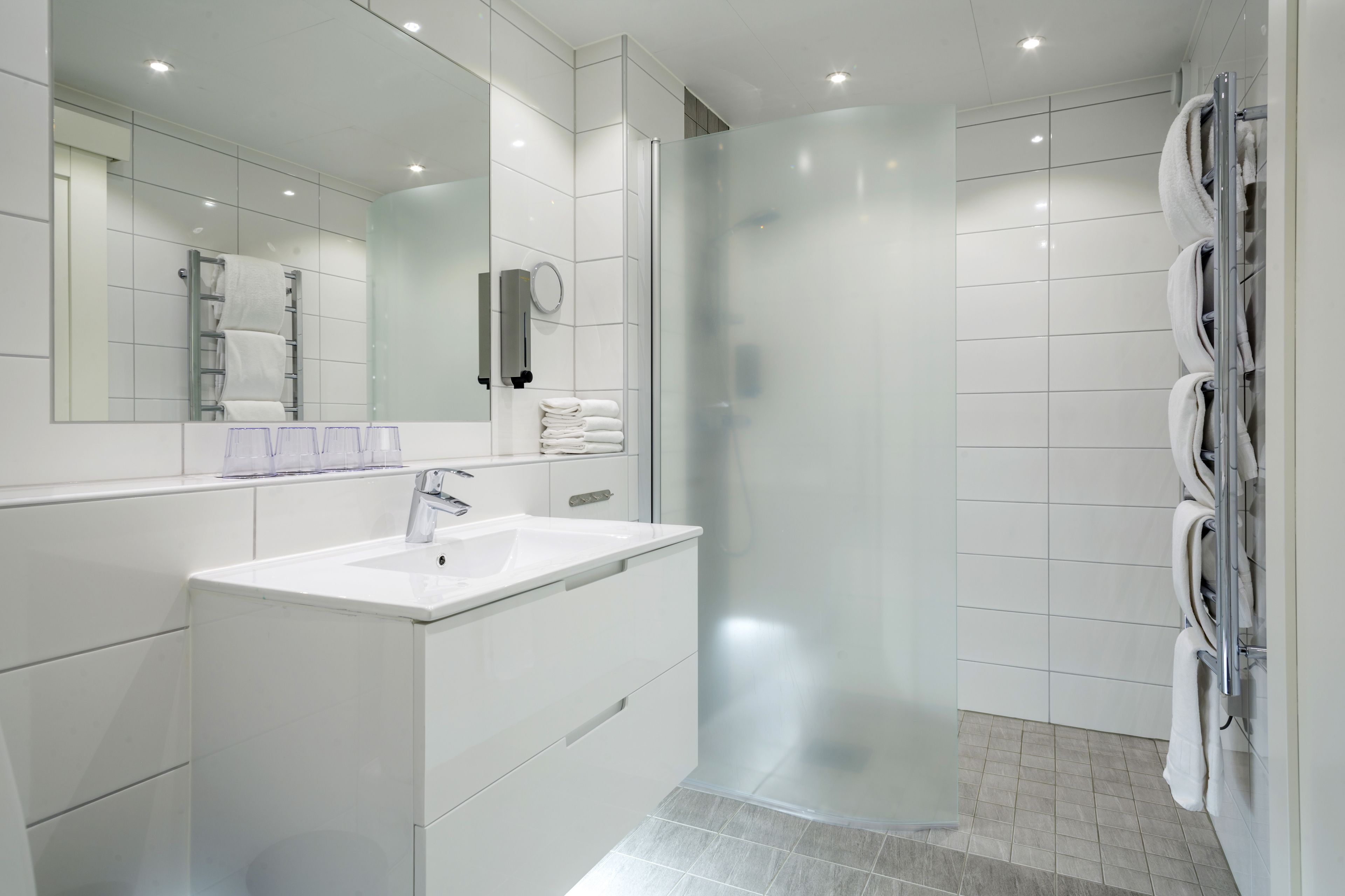 A modern bathroom with a glass-enclosed shower, a white sink, and a towel rack.