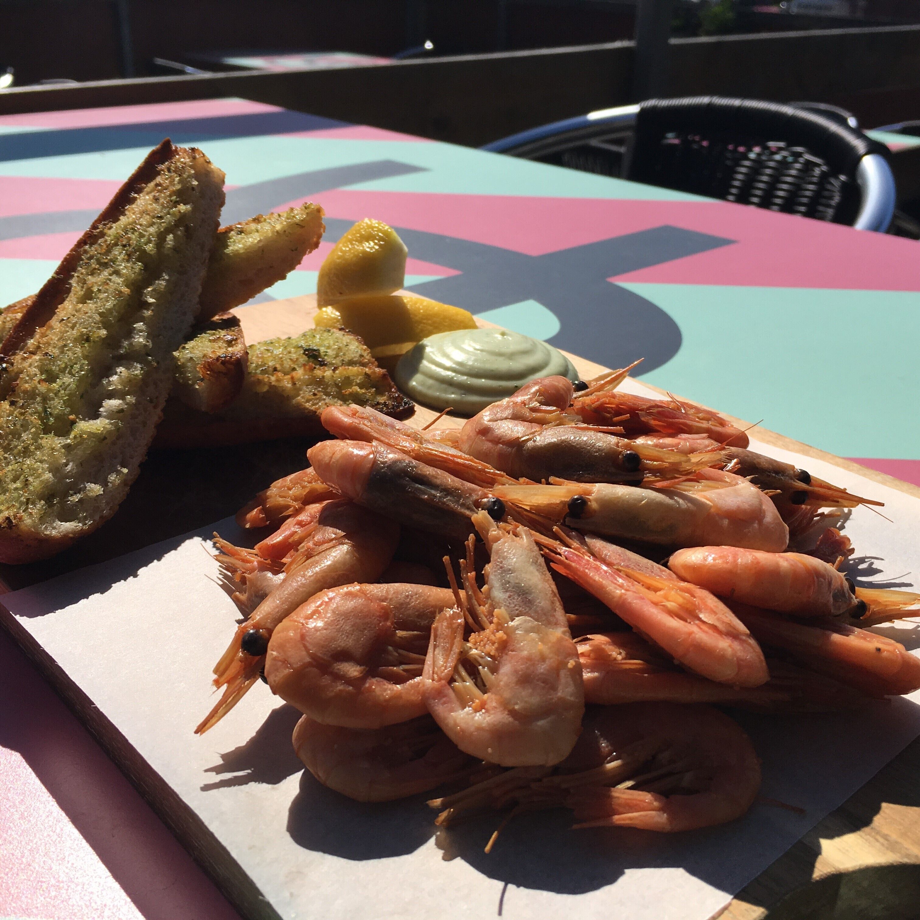 Uma mesa com uma variedade de frutos do mar, incluindo camarões, pão e fatias de limão.