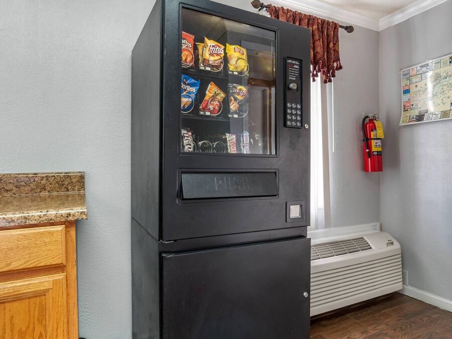 Una cocina con una máquina expendedora negra llena de bocadillos, un extintor y un mapa en la pared.