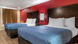 A hotel room with two beds, a red accent wall, a wooden headboard, and a window with curtains. - Econo Lodge Oxford near Choccolocco Park (Oxford)