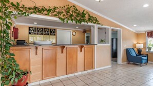 A kitchen with wooden cabinets, a sink, and a clock on the wall. - Econo Lodge Oxford near Choccolocco Park (Oxford)