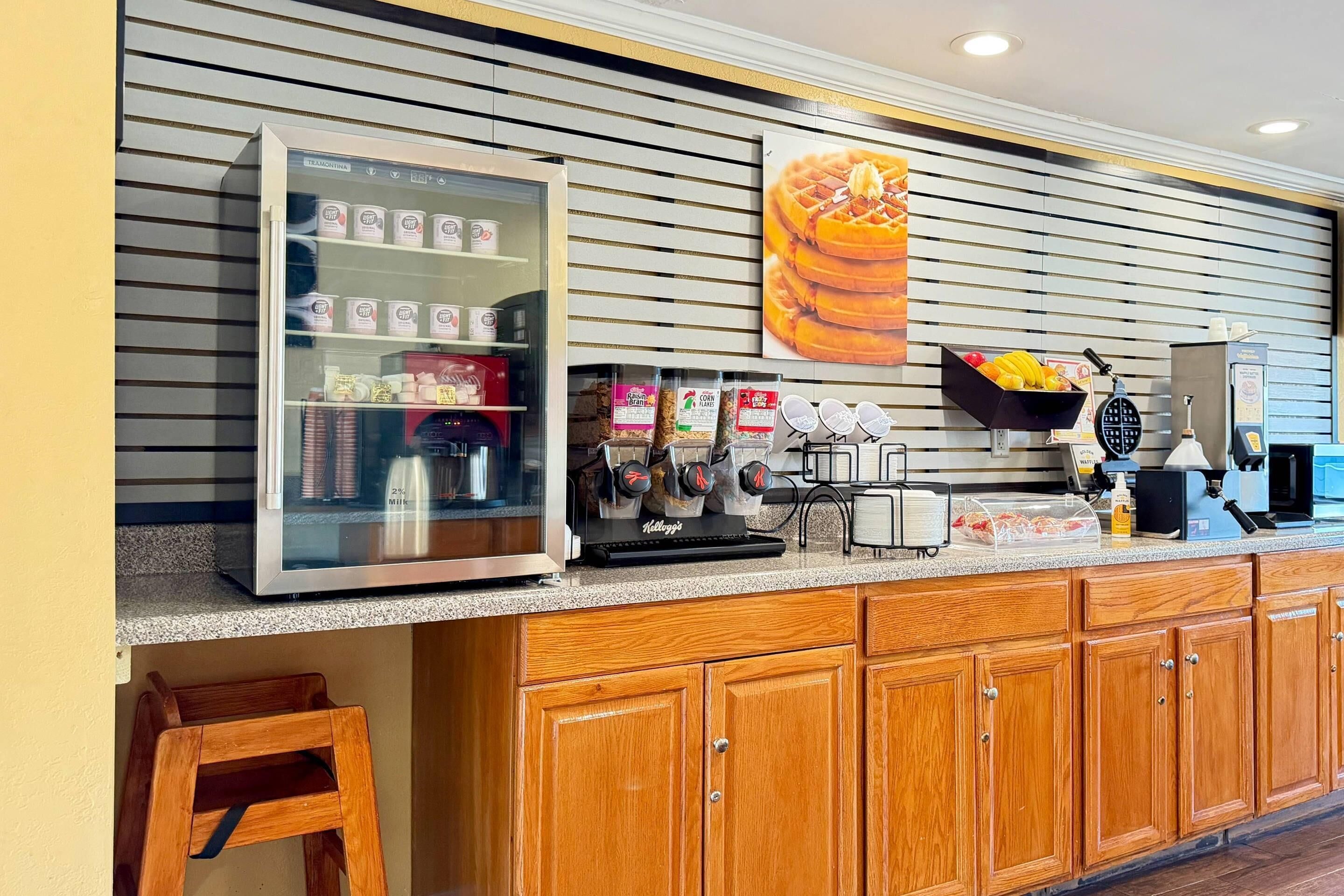 A kitchen area with a refrigerator, coffee machines, and a waffle maker on the counter.
