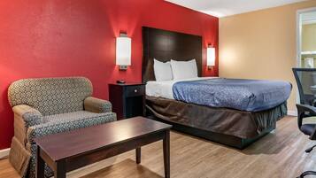 A hotel room with a bed, a sofa, a small table, and two wall-mounted lamps.